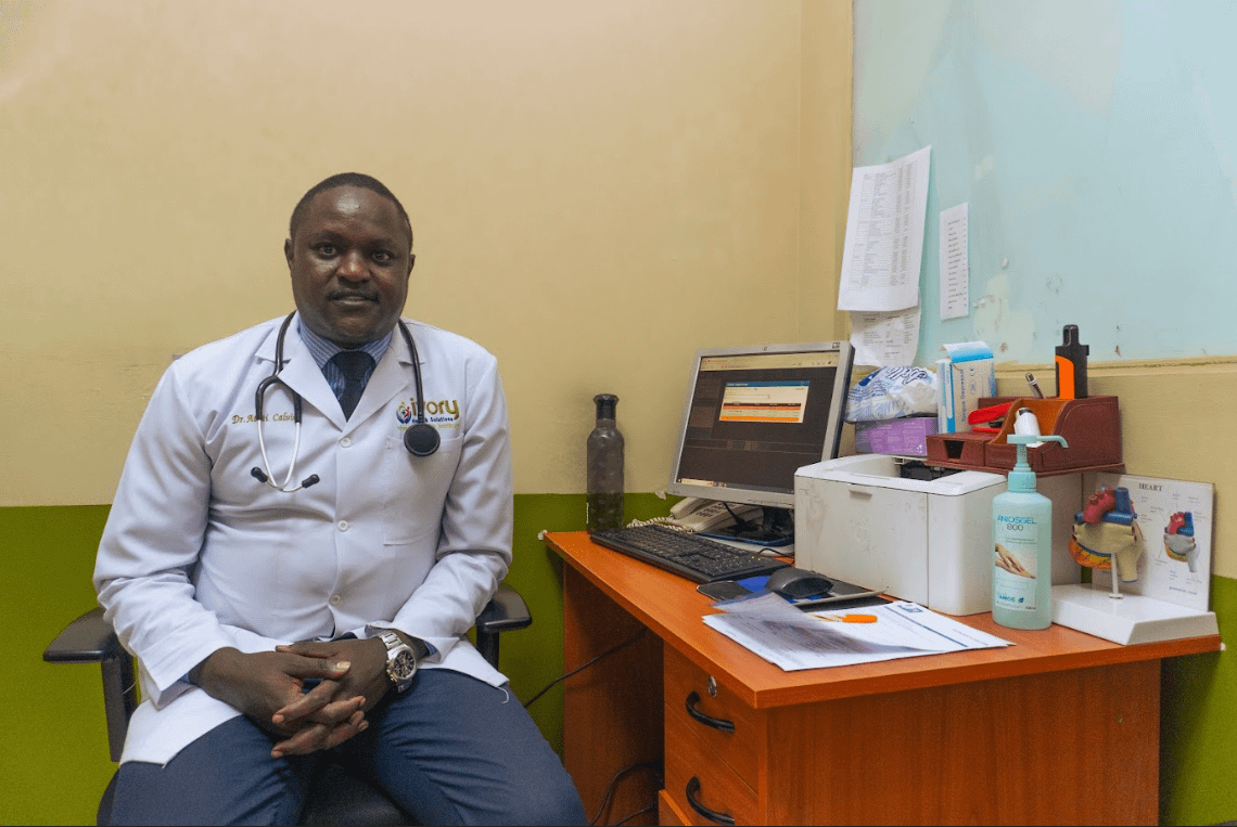 a man in a white coat sitting at a desk