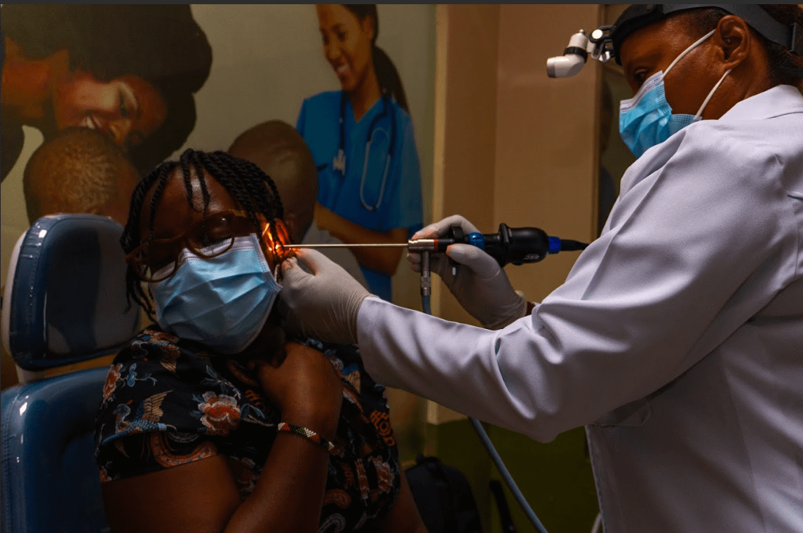 a doctor using a machine to check the ear of a woman