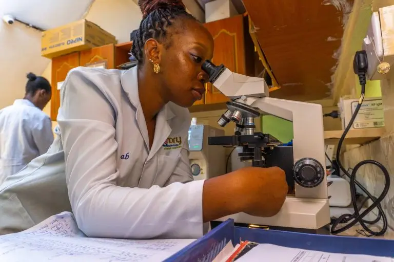 a woman looking through a microscope